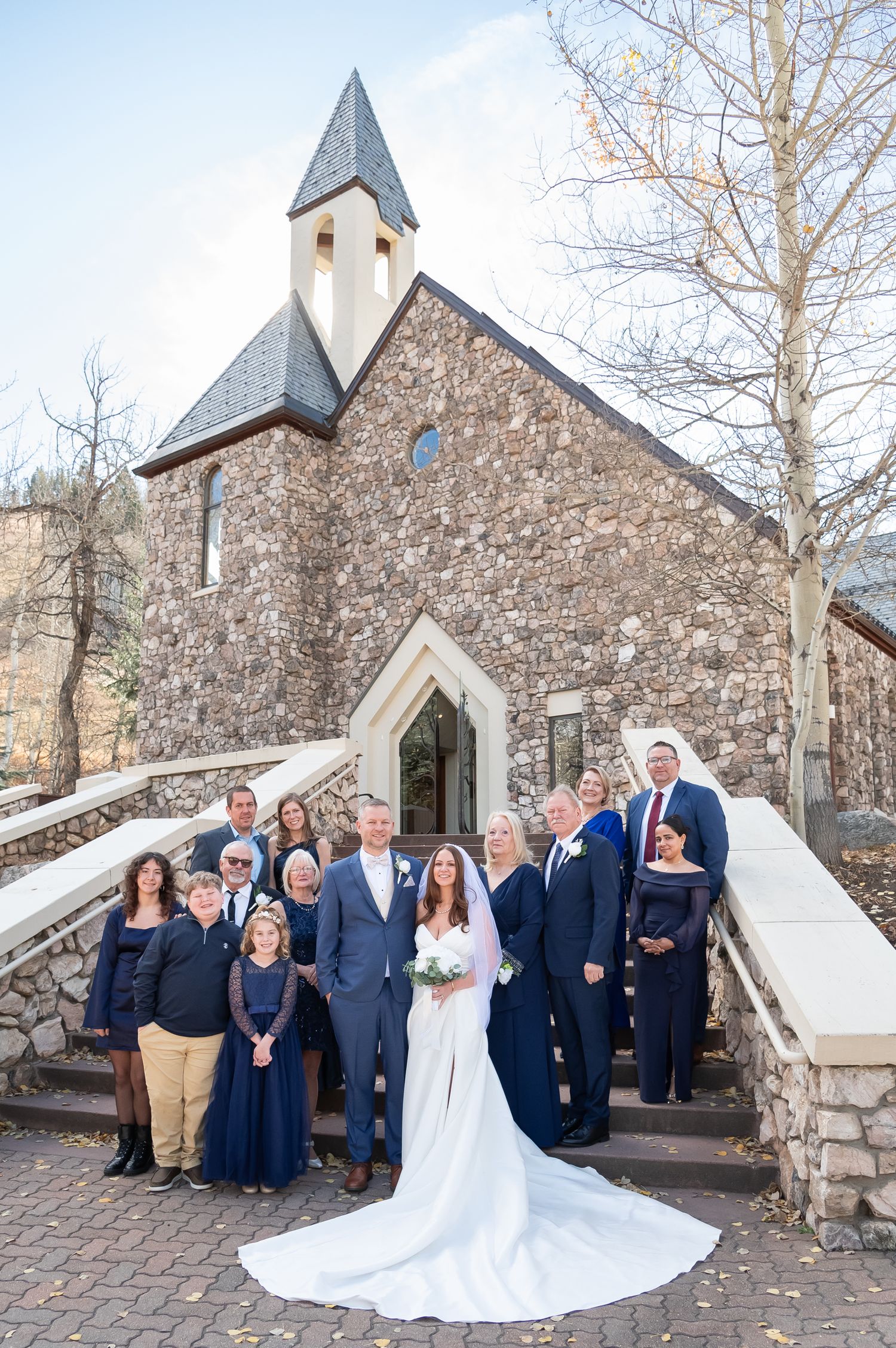 Wedding party poses outside stone Beaver Creek Chapel Colorado