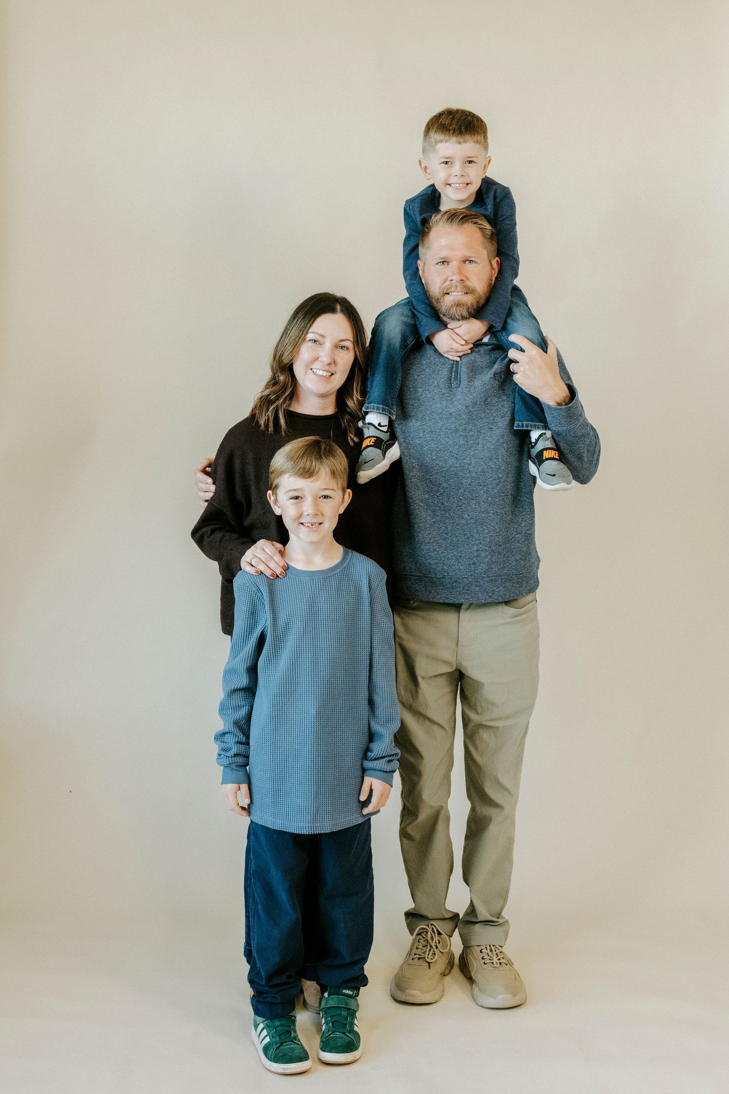 A series of four studio portraits showing a parent and child in casual clothing against a neutral backdrop.
