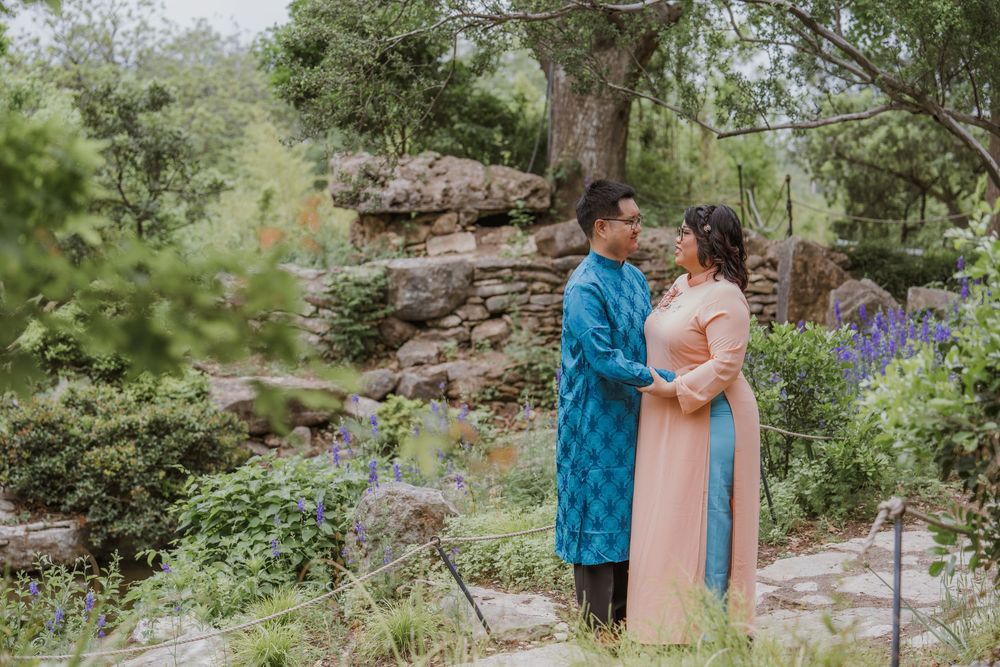 Romantic engagement photos in a garden with stone walls and purple flowers.