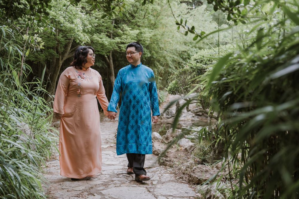 Couple walking along a stone path through a serene garden setting.