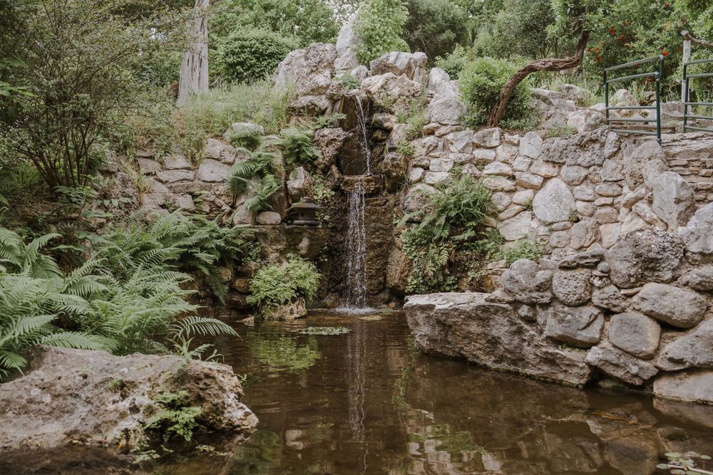 Stone pathway winding through a serene garden with rock walls and water features.