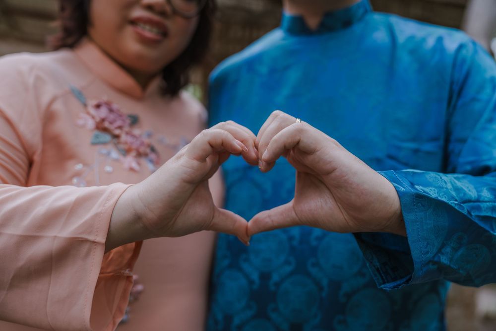 Hands forming heart shapes against a blurred garden background.