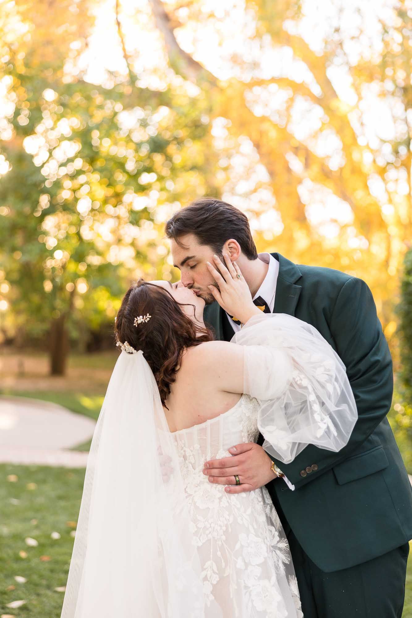 A flowing white wedding gown with a long train spreads gracefully across a sunlit lawn at golden hour.