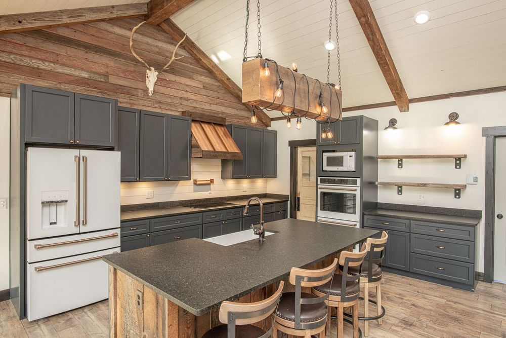 Contemporary kitchen with gray cabinets, wood beams, and stainless steel appliances showcases open concept design.