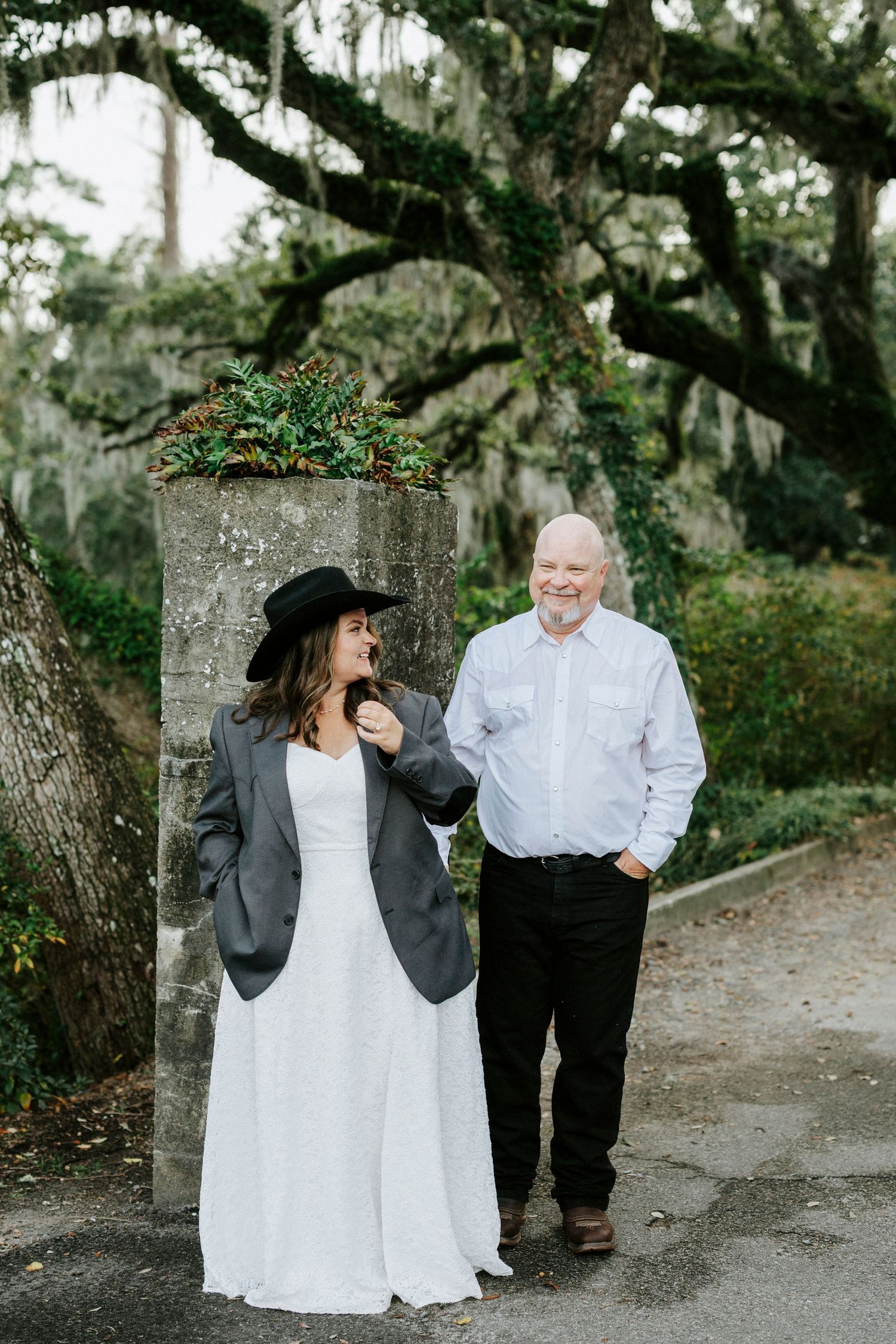 Couple sharing a tender moment on a tree-lined pathway during their wedding day.
