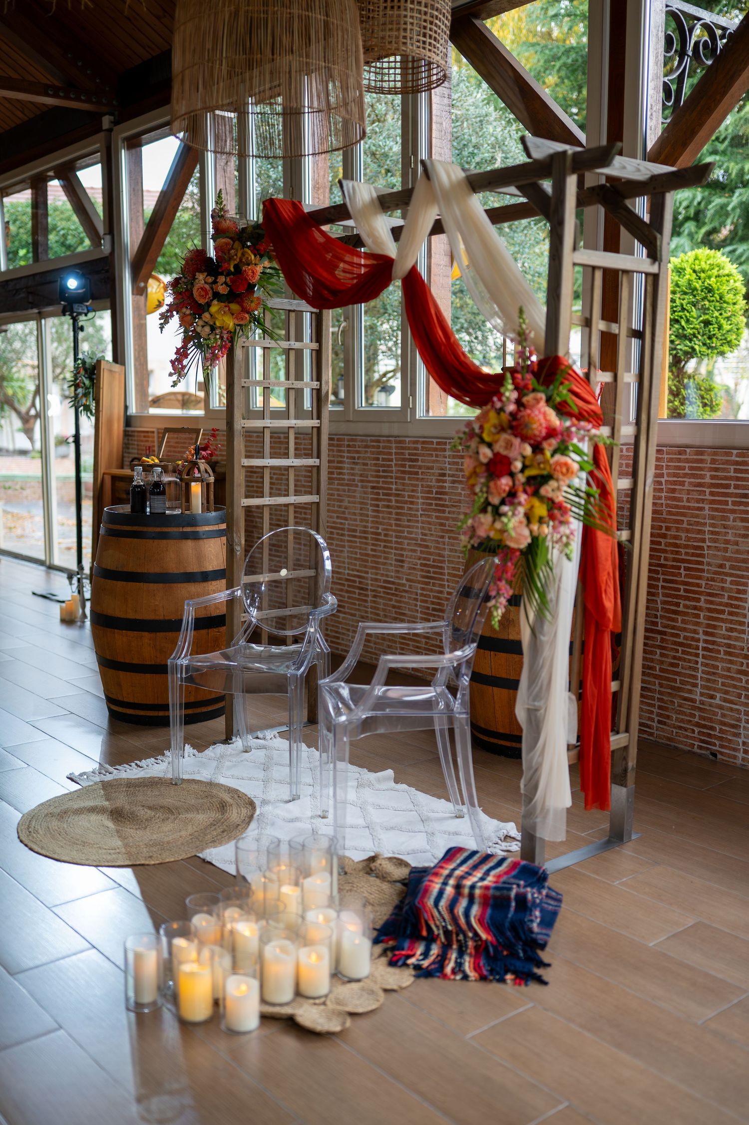Intérieur rustique du lieu de mariage avec des fûts en bois, des bougies et des décorations florales rouges et blanches le long d'un mur de