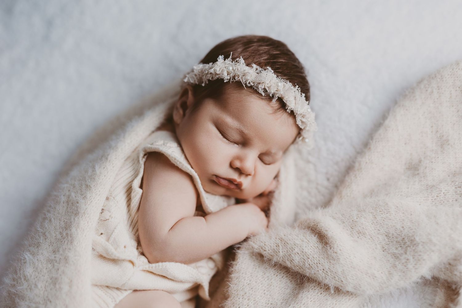 Delicate newborn photography series featuring baby with floral crown on soft blanket.