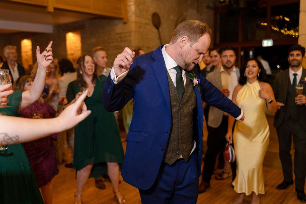Wedding guests dancing and celebrating on a dimly lit dance floor during an evening reception.
