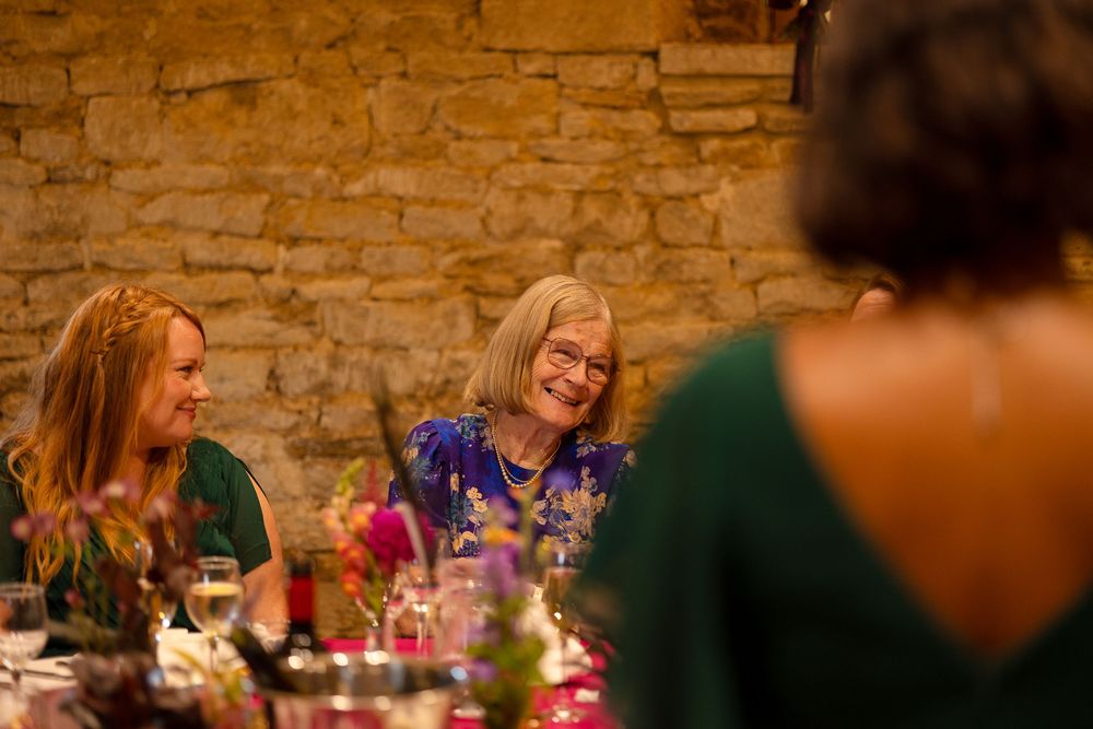 Guests enjoying conversation at elegant wedding reception with stone walls and ambient lighting.