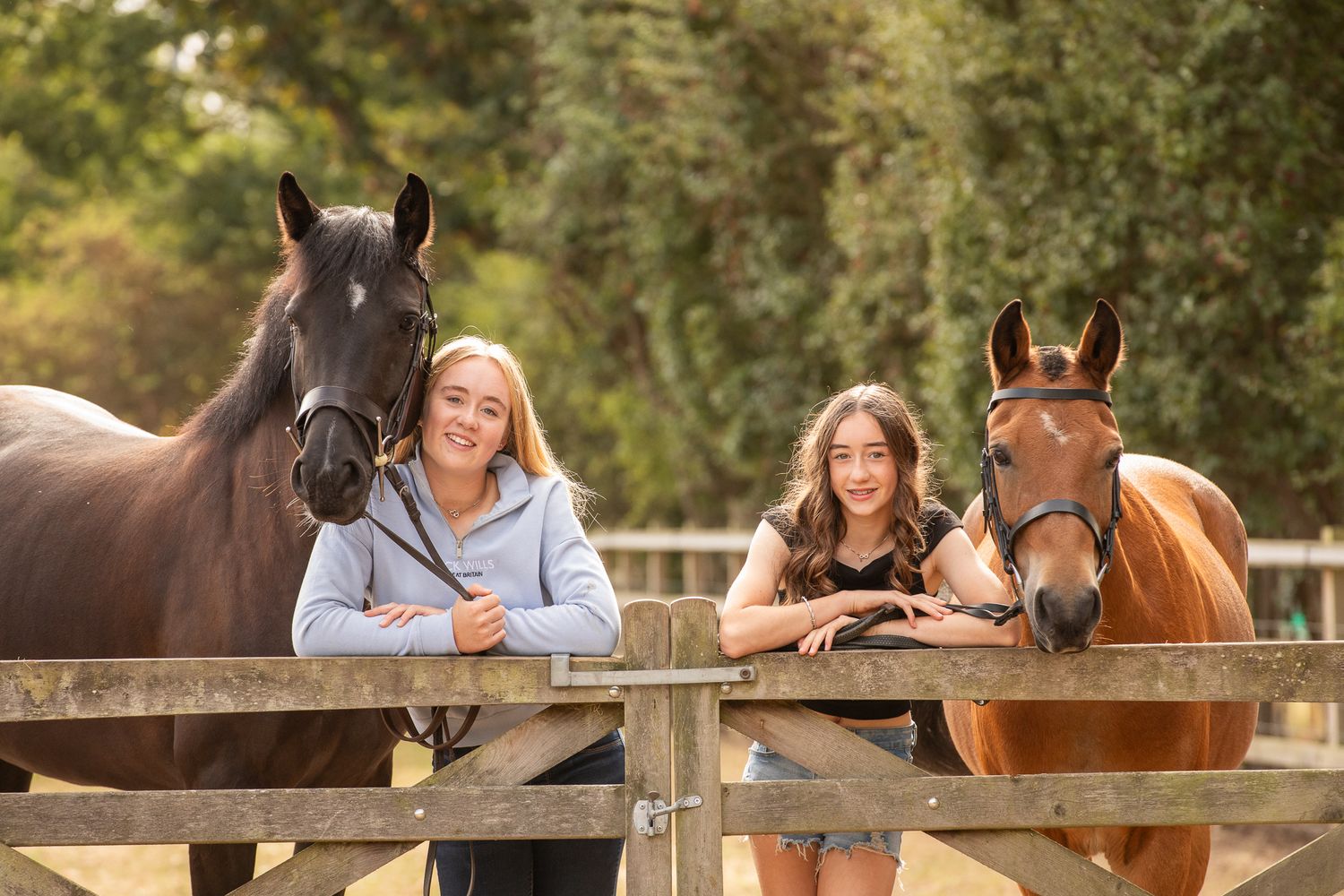 A horse and its rider enjoy an outdoor photoshoot session near rustic wooden fencing on a sunny day.