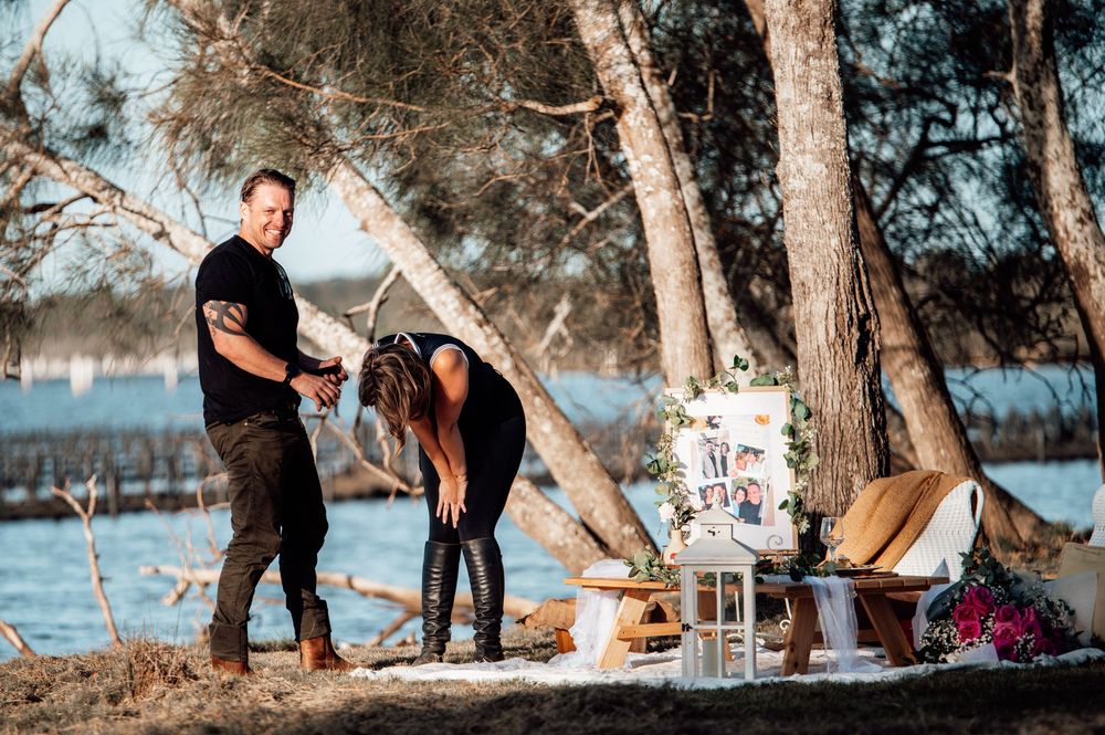 A couple shares a romantic moment by the water's edge during a sunset engagement photo session.