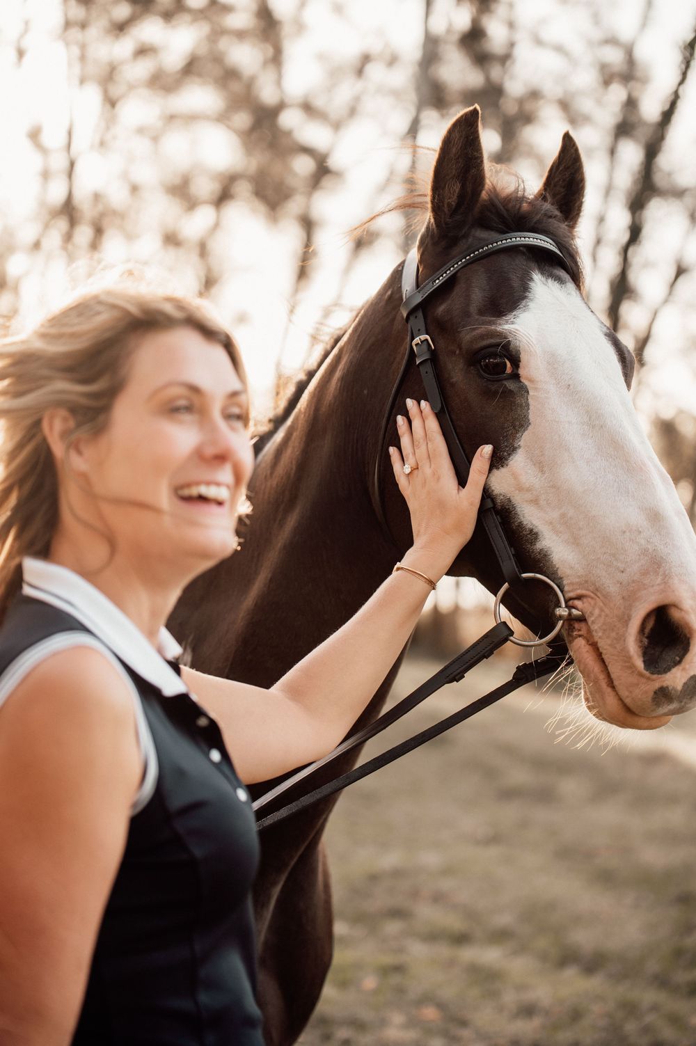 Close-up of brown and white horse with rider showing affection in warm sunset lighting.