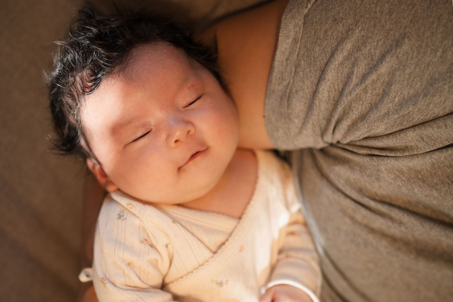 A sleeping baby rests peacefully in a cozy bed with soft lighting.