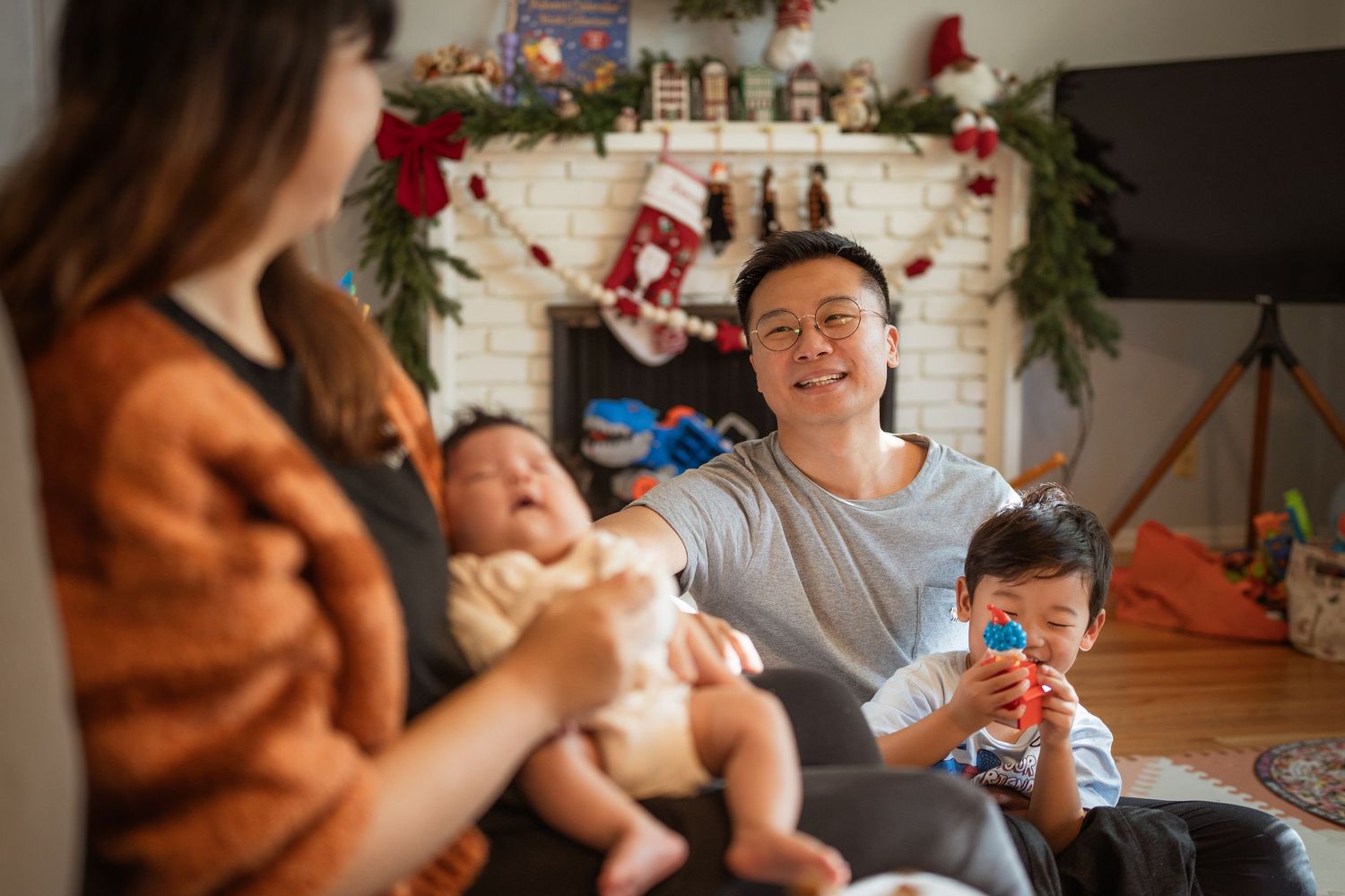 Family enjoying a cozy Christmas moment together on a playmat with festive decorations in the background.