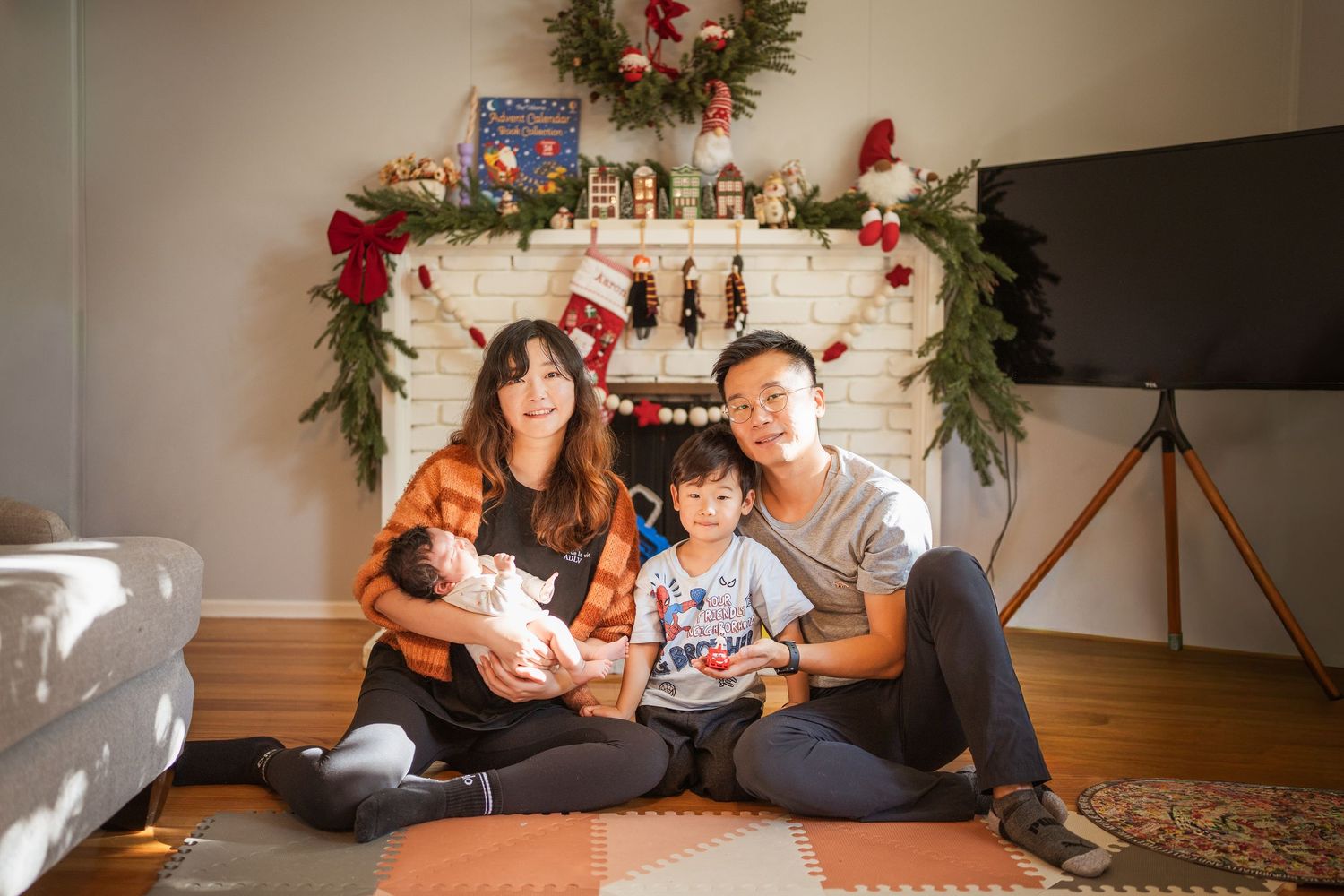 A festive Christmas photo shoot setup with holiday decorations and garland in a cozy living room.