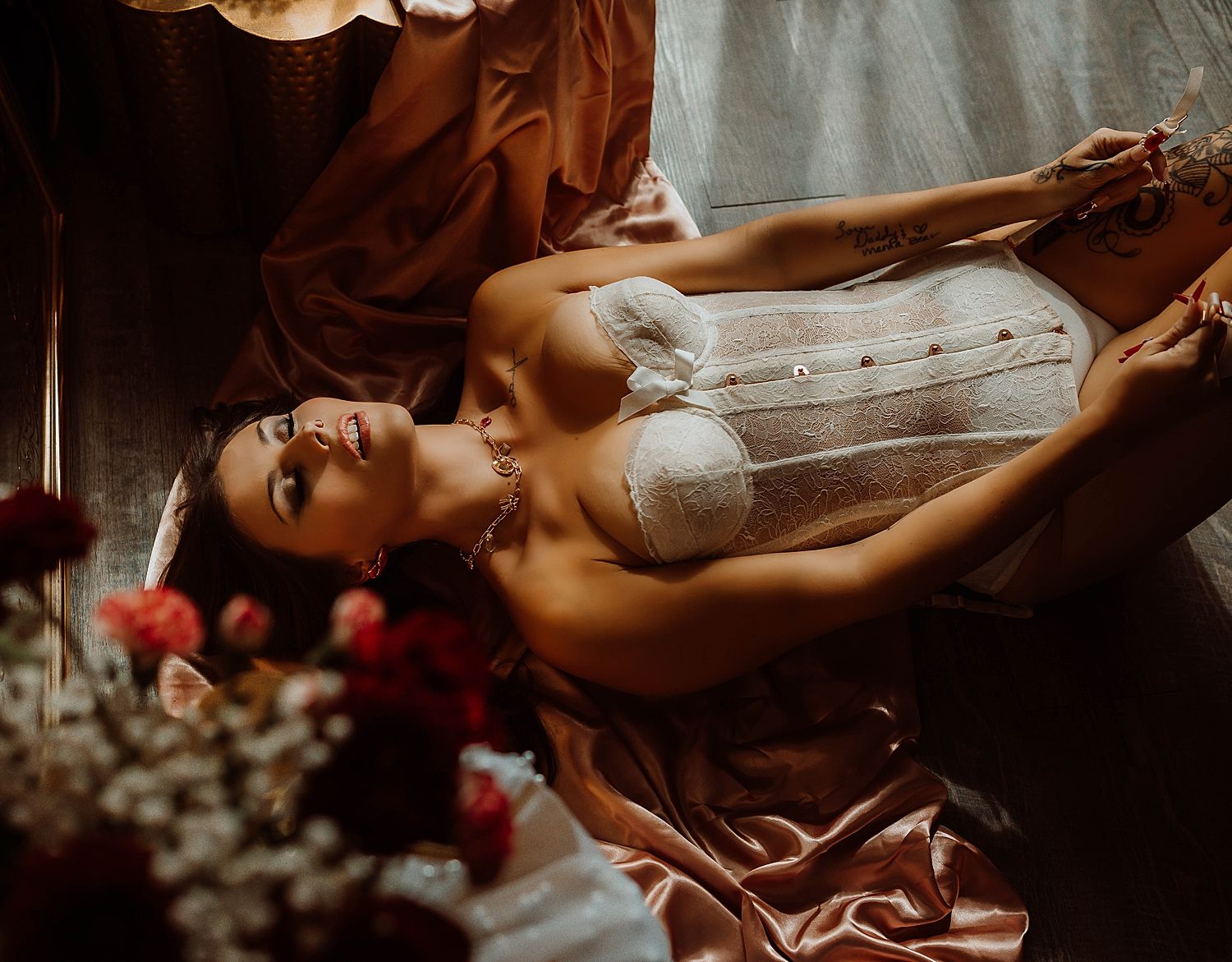 Brunette in white corset lies across floor for Valentine's Day  boudoir session.