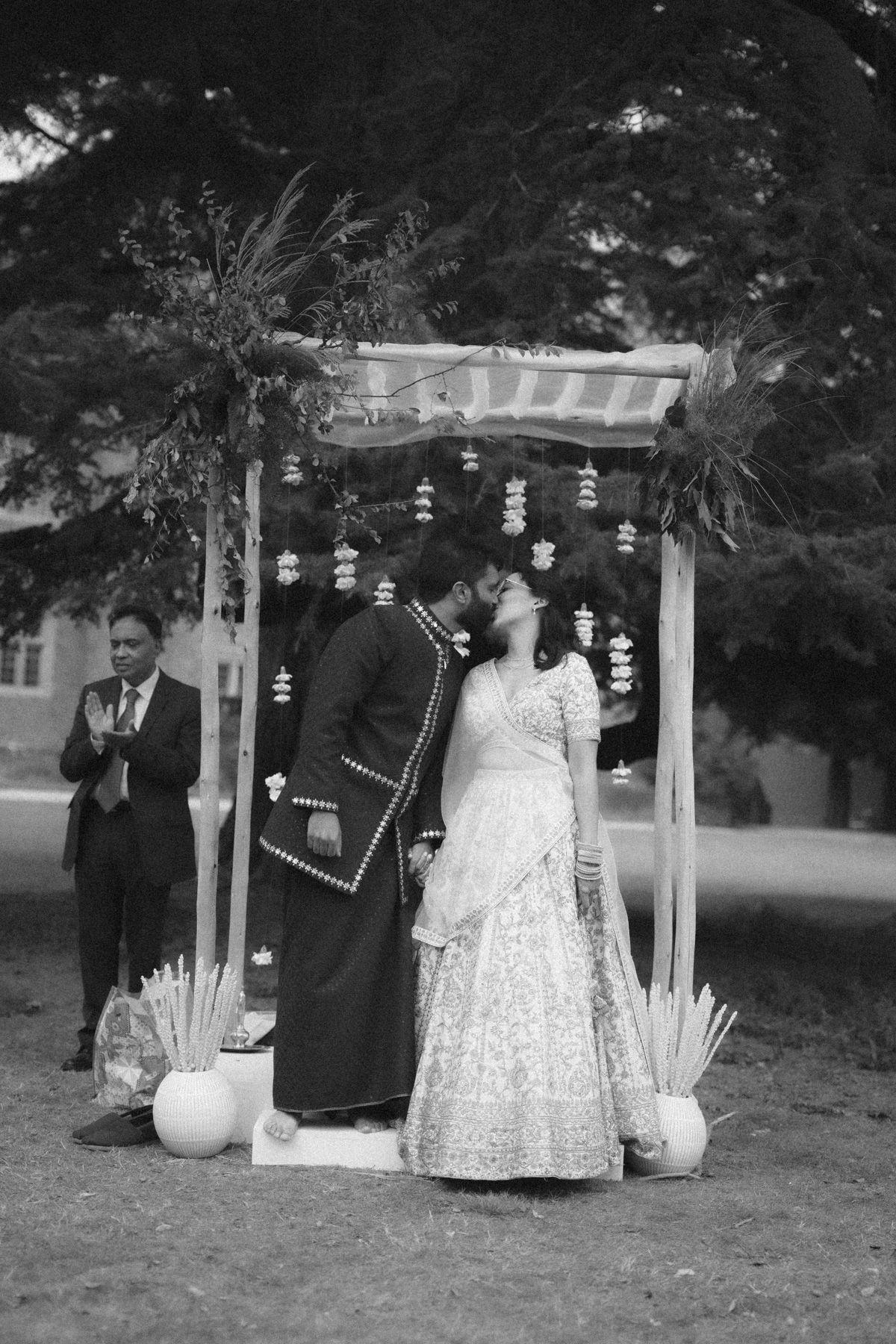 A series of wedding photos showing a couple under a decorated outdoor arbor with hanging lanterns at dusk.