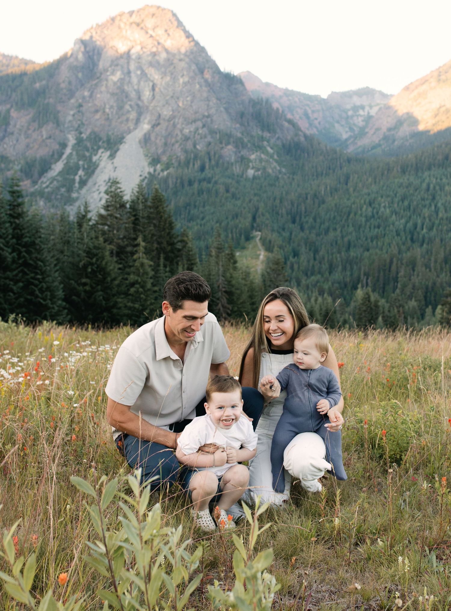 A series of candid photos showing a couple with a young child playing and embracing outdoors against a mountain backdrop.