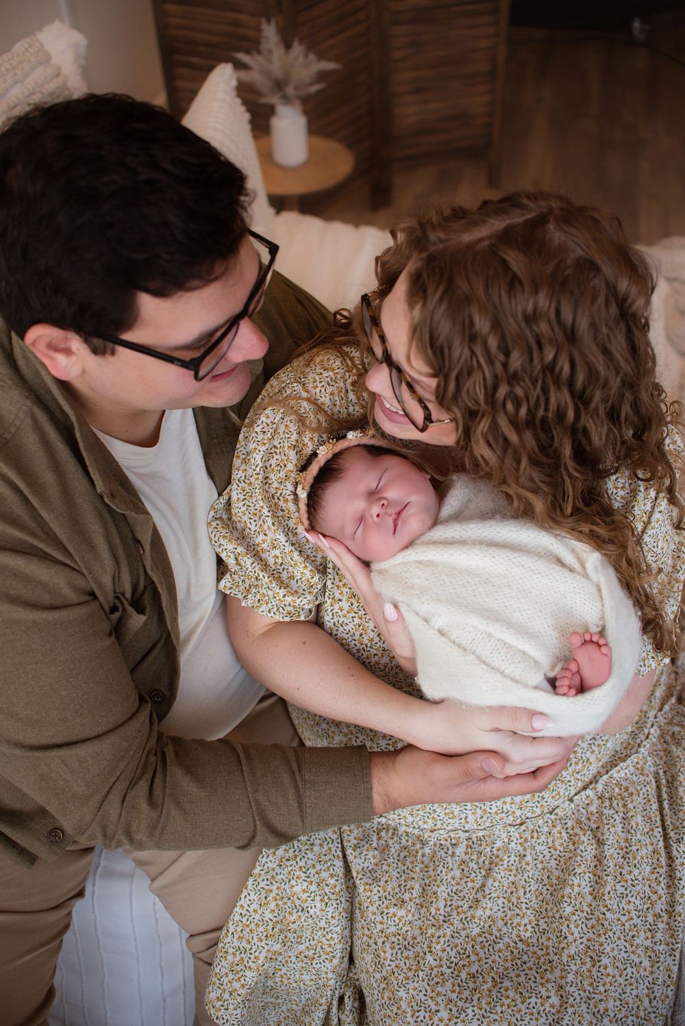 Cozy family portrait session on brown couch with warm intimate lighting.