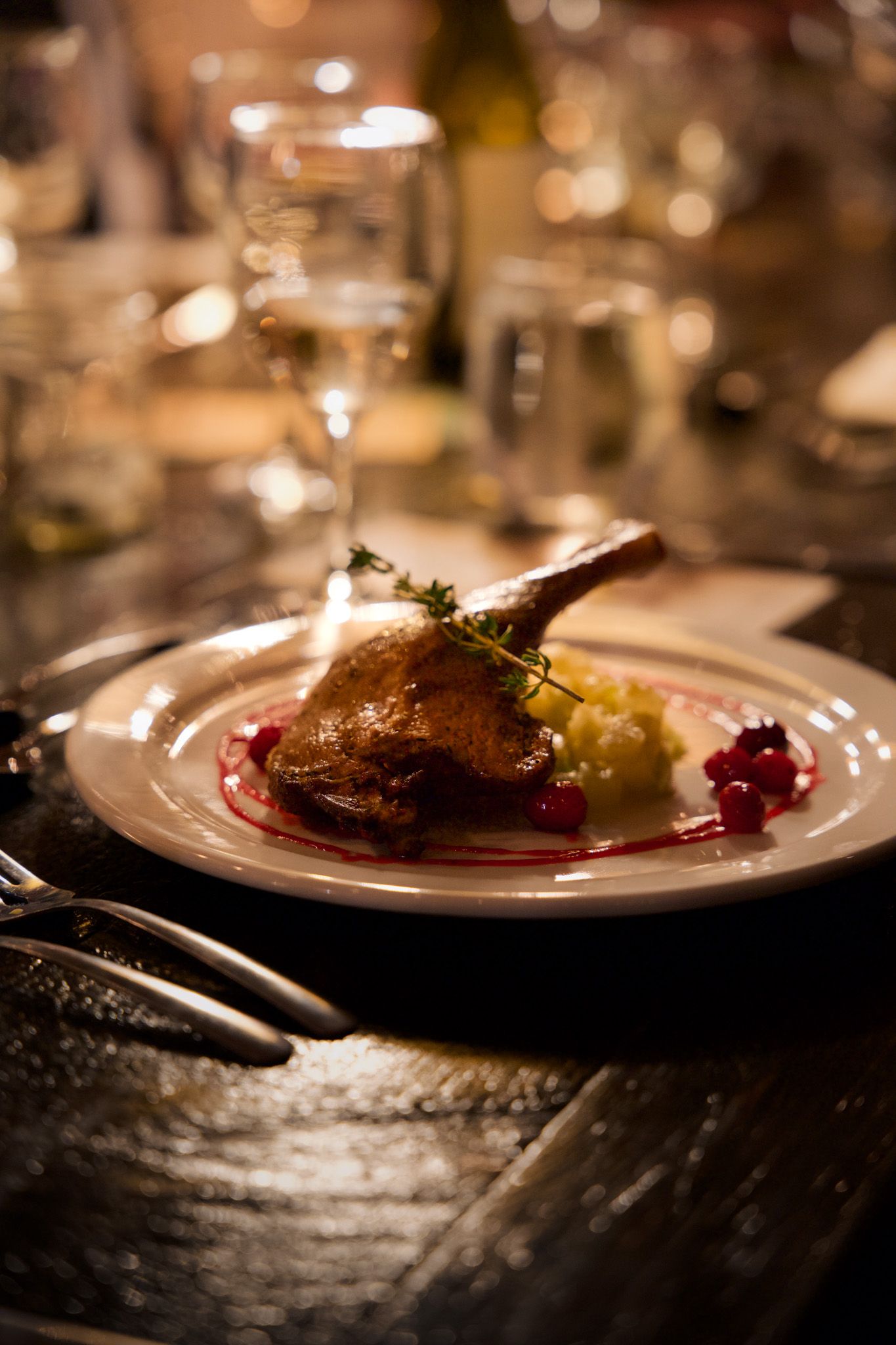 Gourmet duck leg with sauce and garnish plated elegantly in warm lighting.
