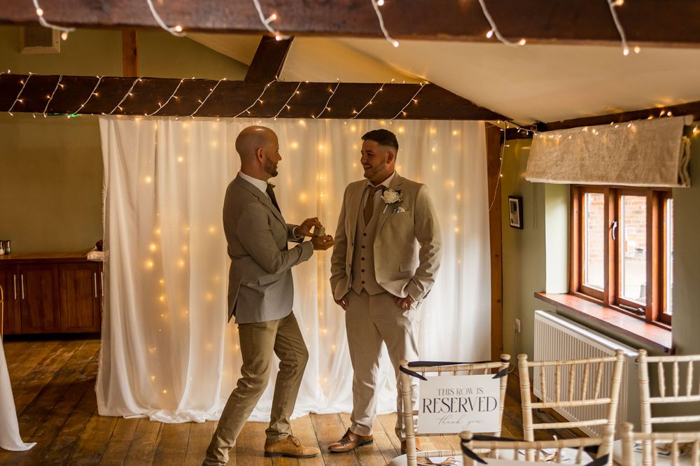 Wedding ceremony in progress with guests watching in a wood-paneled room with string lights.