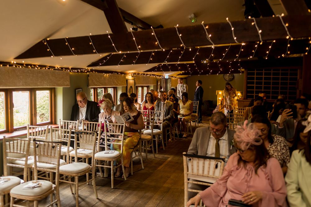 Indoor wedding ceremony space decorated with warm lighting and white curtain backdrop.