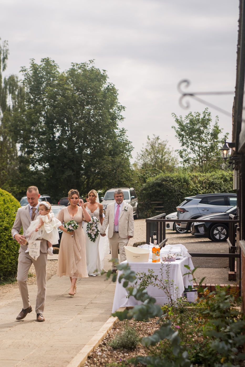 Wedding party walking outside venue carrying drinks and celebrating.