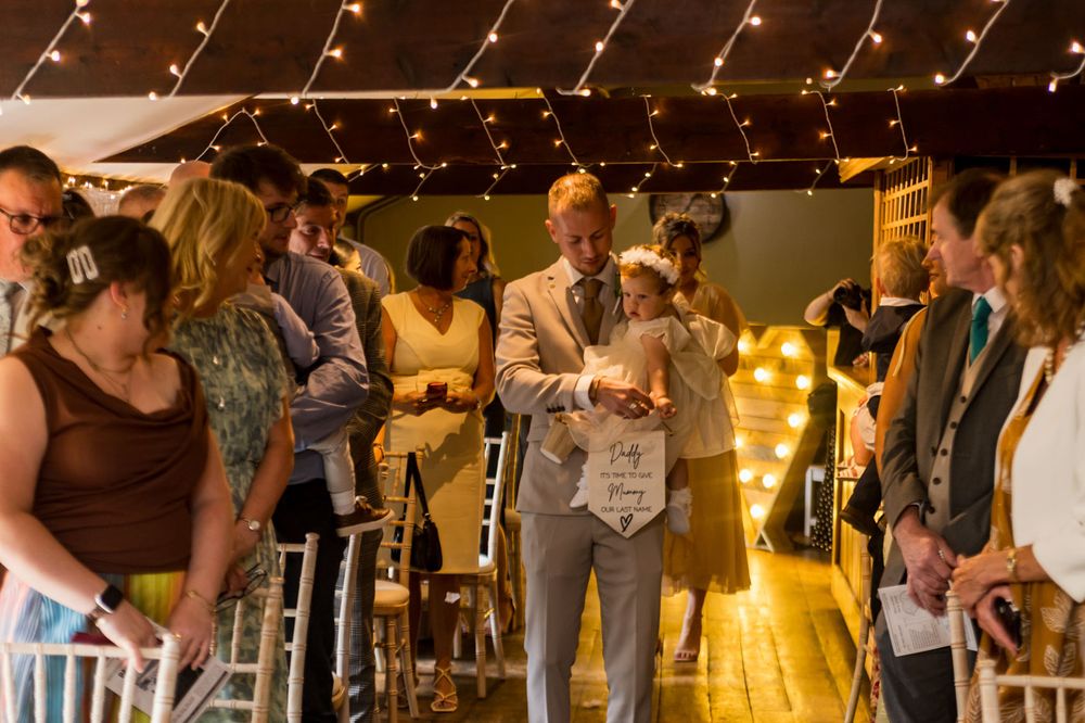 Guests mingle under warm string lights at an indoor wedding reception venue.
