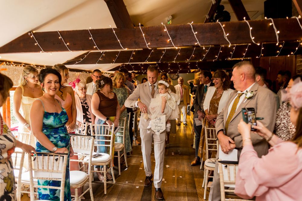 Wedding ceremony guests seated in rows of white chairs under string lights.
