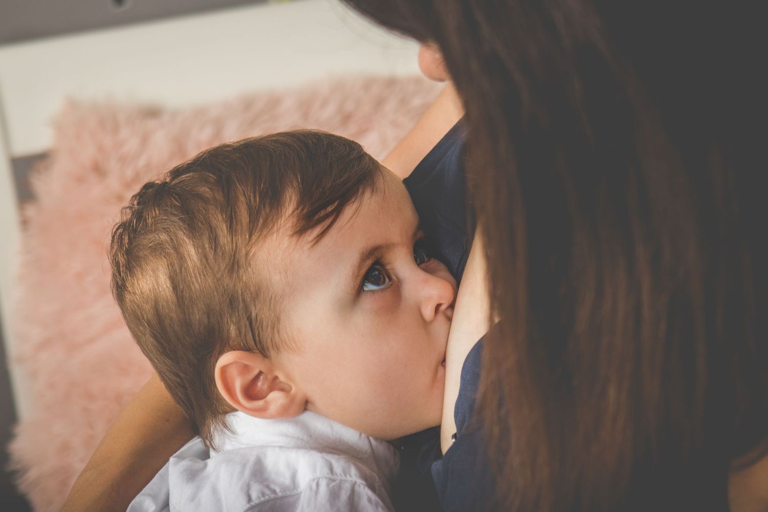 Mamă și bebe privindu-se în timpul alăptării