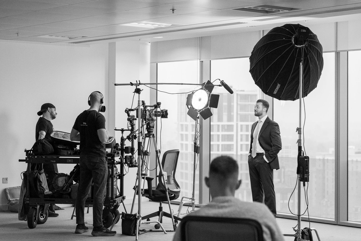 Behind-the-scenes photo shoot setup in a bright studio with lighting equipment and crew members at work.