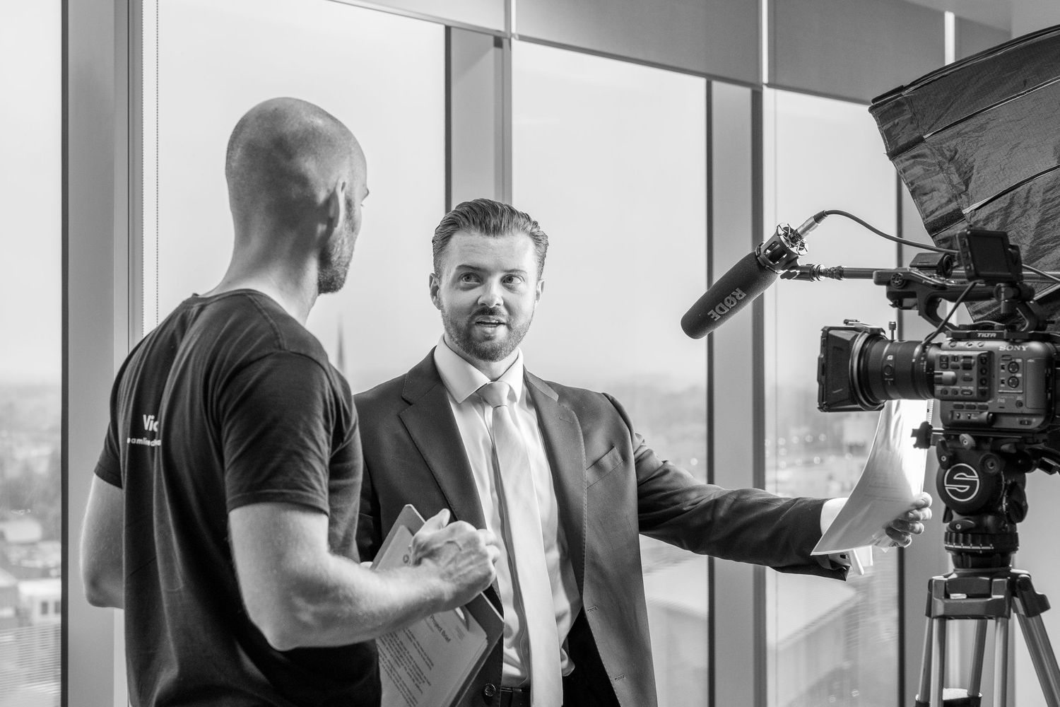 A black and white behind-the-scenes photo shows camera operators and crew members working on a film production set.