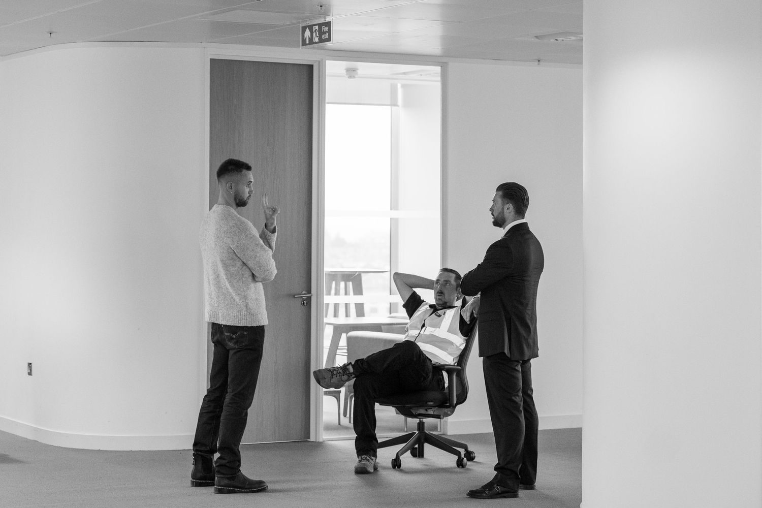 Two office workers demonstrate proper ergonomic posture and workstation setup in a bright modern workspace.
