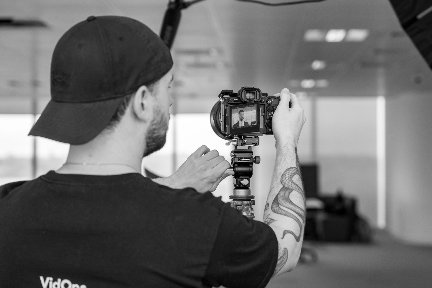 Film crew members collaborate while setting up professional video equipment in an office.