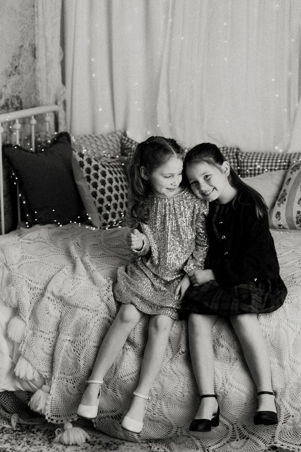 Two children sit together on a vintage floral couch in black and white photograph series.