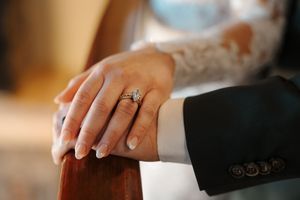Wedding couple's hands intertwined showing off engagement and wedding rings.