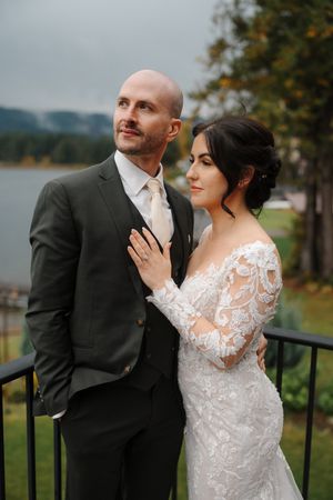 A romantic wedding couple poses together in a series of outdoor portraits with a lake and autumn scenery in the background.