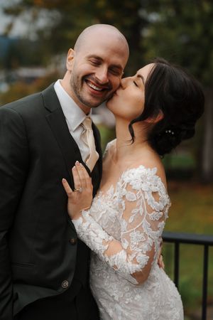A romantic wedding couple share intimate moments in formal attire against an autumn backdrop.