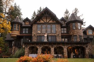 Luxury Tudor-style mansion with stone facade and multiple gabled roofs surrounded by autumn trees.