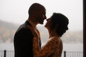 A silhouetted couple in an intimate embrace stands against a misty background during their wedding day.