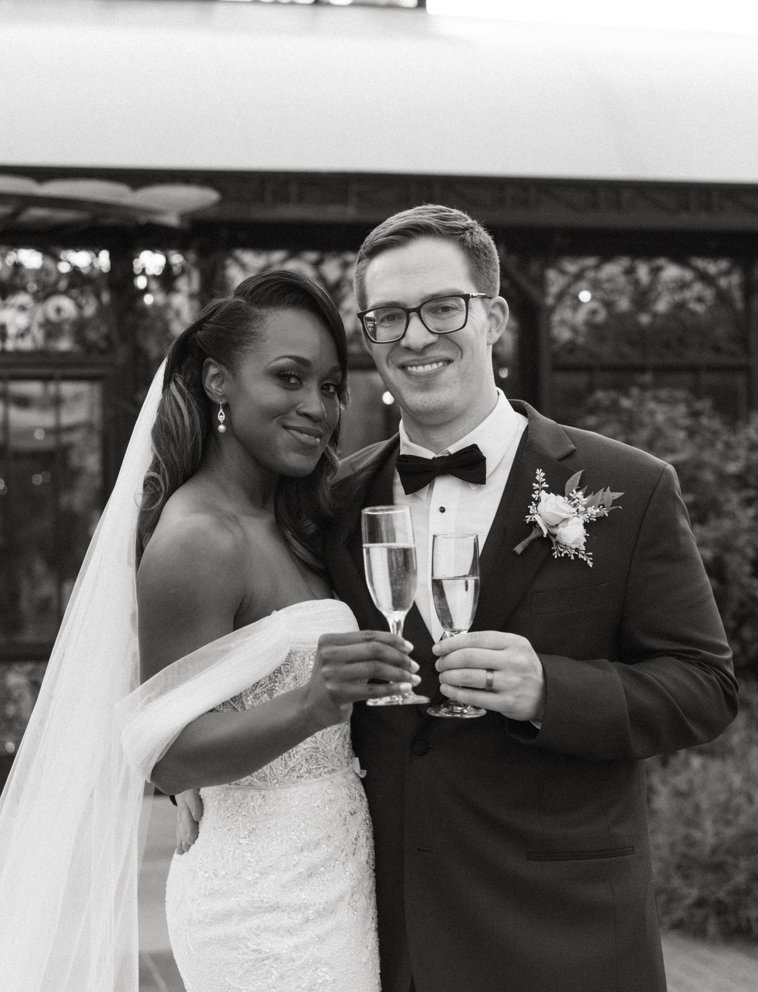 A happy couple in wedding attire share champagne toasts and joyful moments in a series of black and white photos.