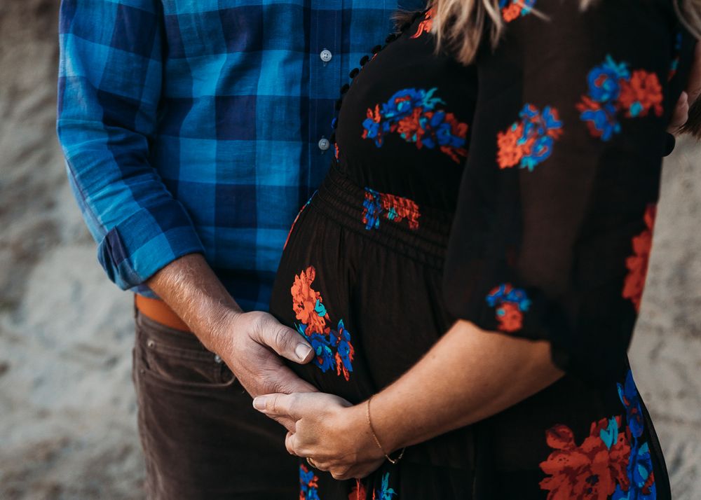 Close-up of hands holding a black floral dress against a blue plaid shirt in a fashion styling scene.