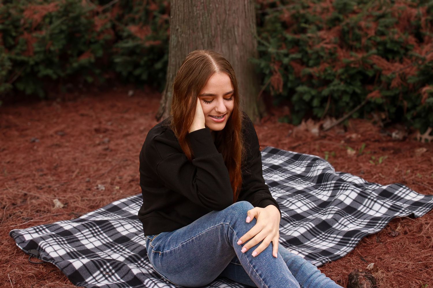 Cozy, outdoor senior lifestyle, portrait of a woman sitting on a blanket surrounded by Autumn tones in Michigan