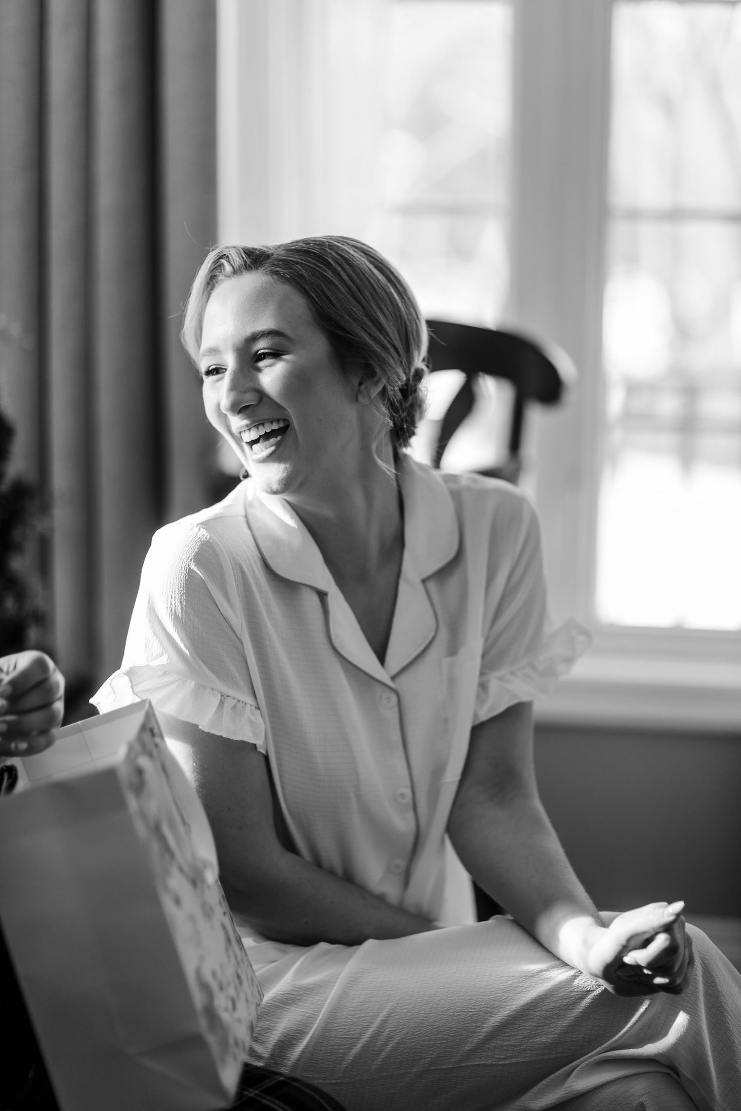 Black and white photo series showing someone in white shirt lounging and laughing on bed in bright sunlit room.