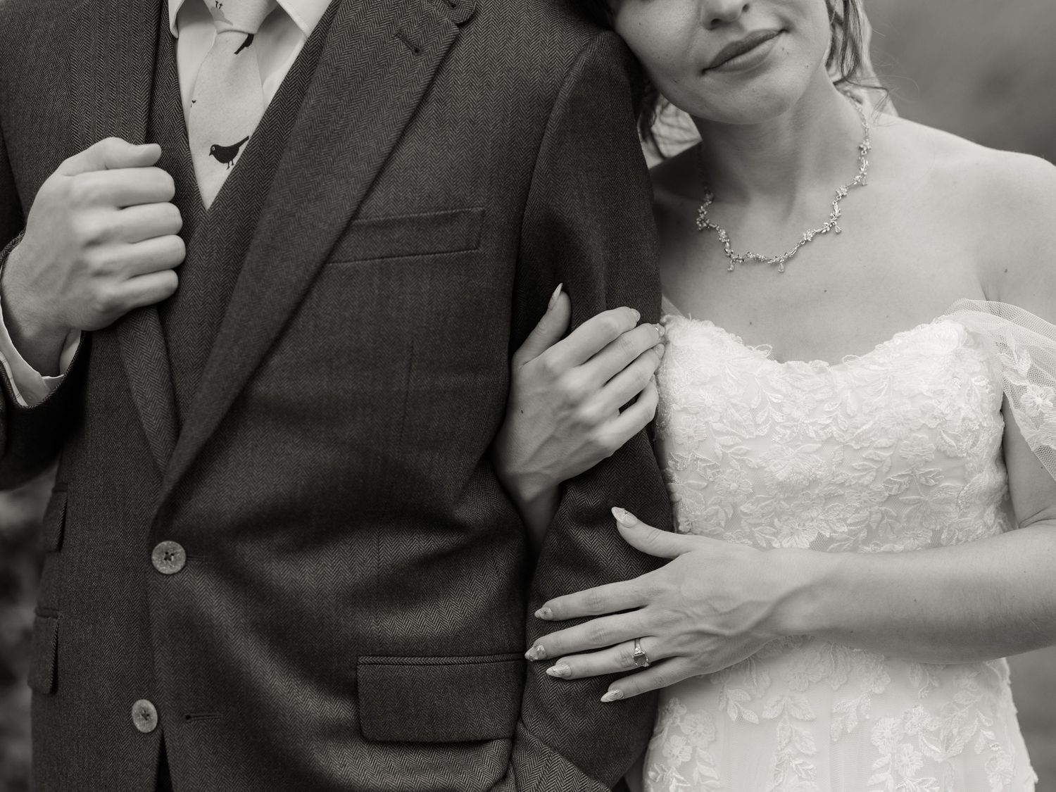 A black and white wedding photo showing a tender embrace between a couple in formal attire.