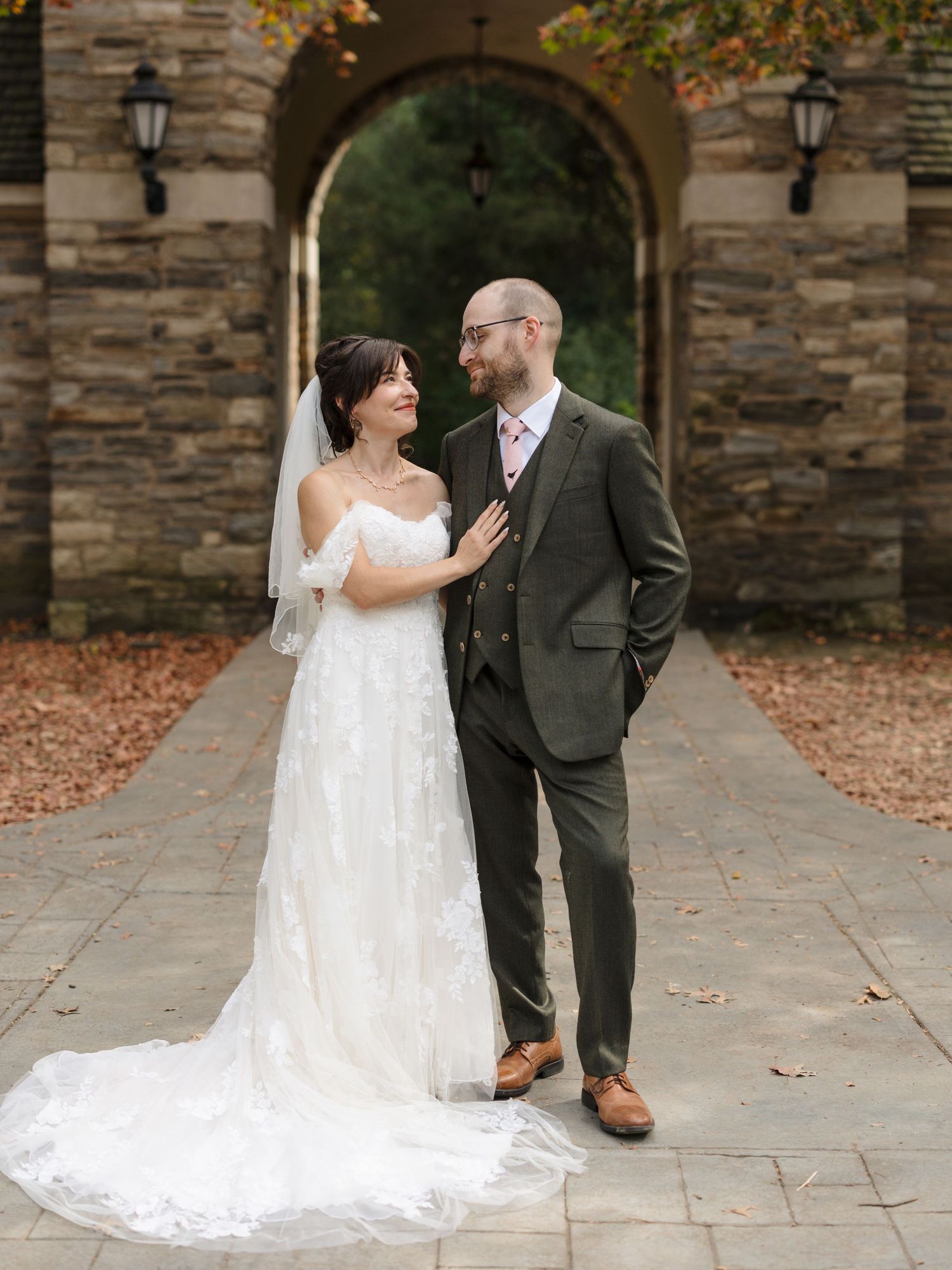 A bride and groom share intimate moments in front of a stone wall during their autumn wedding photo session.