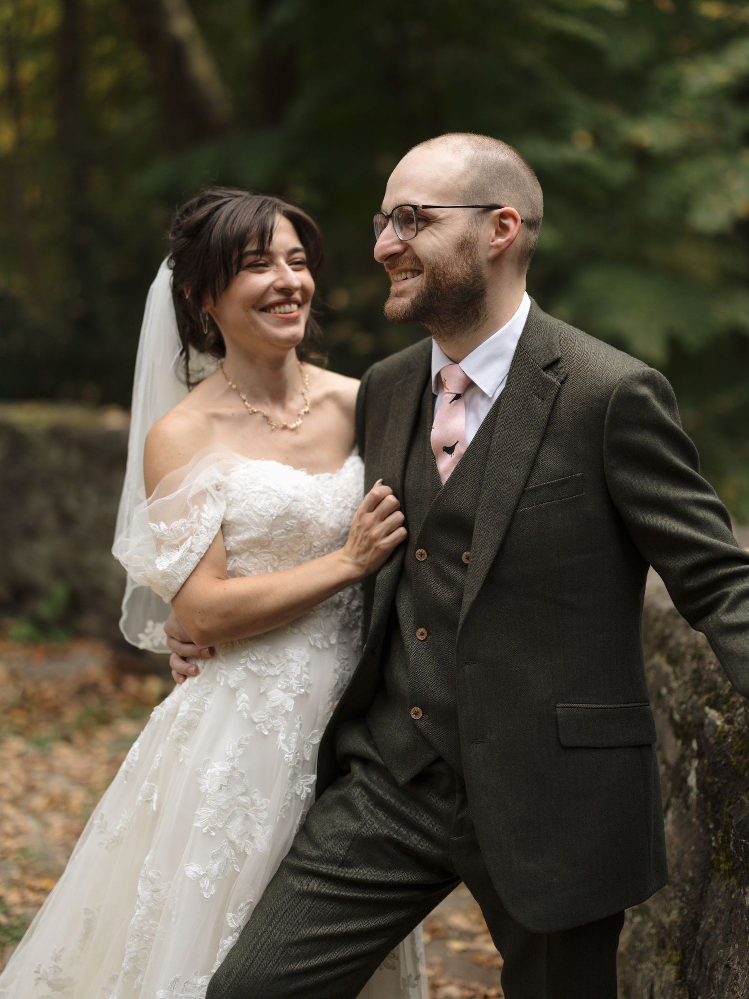 A romantic wedding couple shares tender moments in an outdoor forest setting wearing traditional wedding attire.