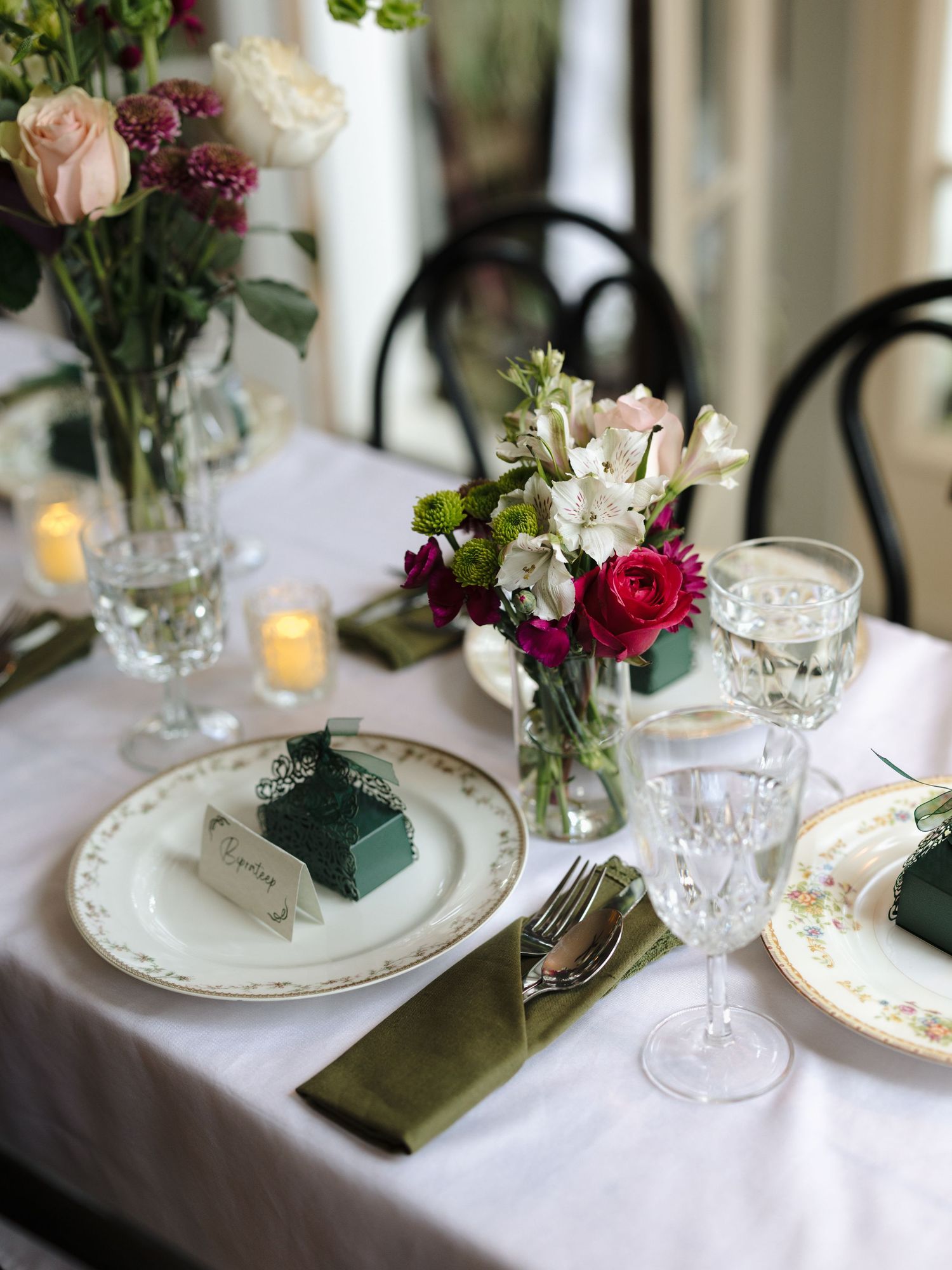 Elegant table settings with white plates, wine glasses, and pink and red floral centerpieces create a romantic dining atmosphere.
