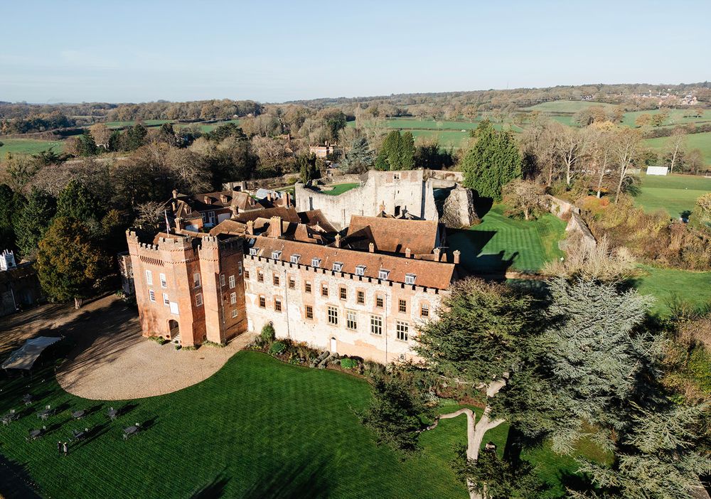 Panoramic view of a historic English manor house and estate with manicured lawns and countryside surroundings.