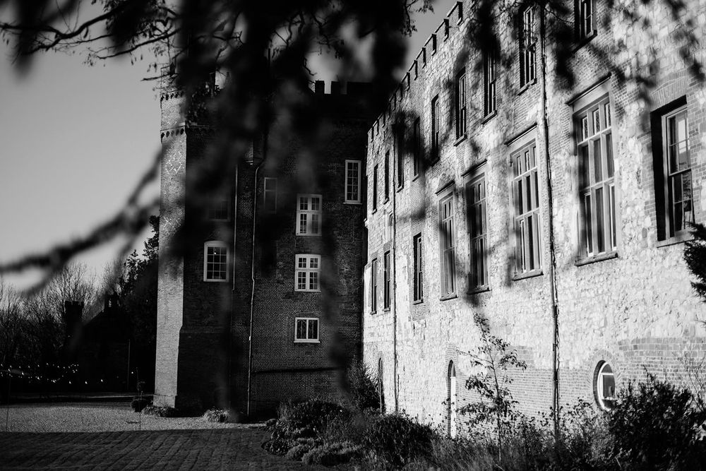 Black and white architectural photograph of a historic stone building exterior with dramatic shadows and textured walls.